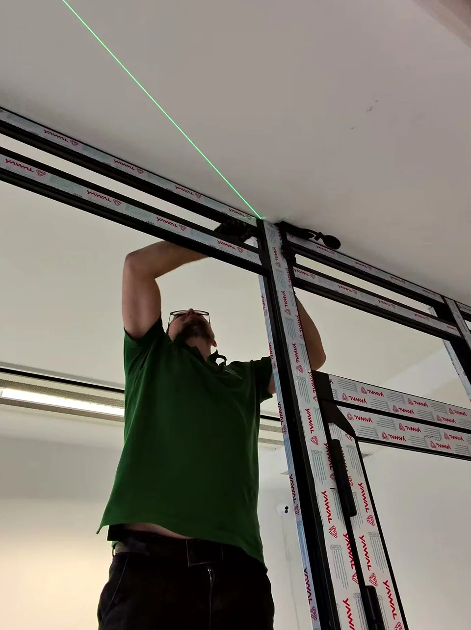 Monter przy górnym profilu ścianki YAWAL, z widoczną linią lasera na suficie